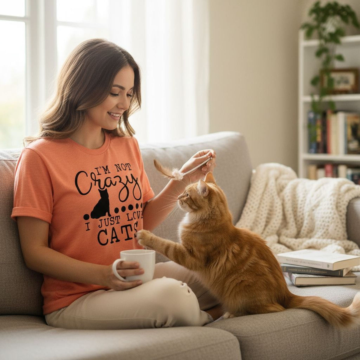 Orange unisex t-shirt worn by a woman, featuring a black cat graphic and “I just love cats”.