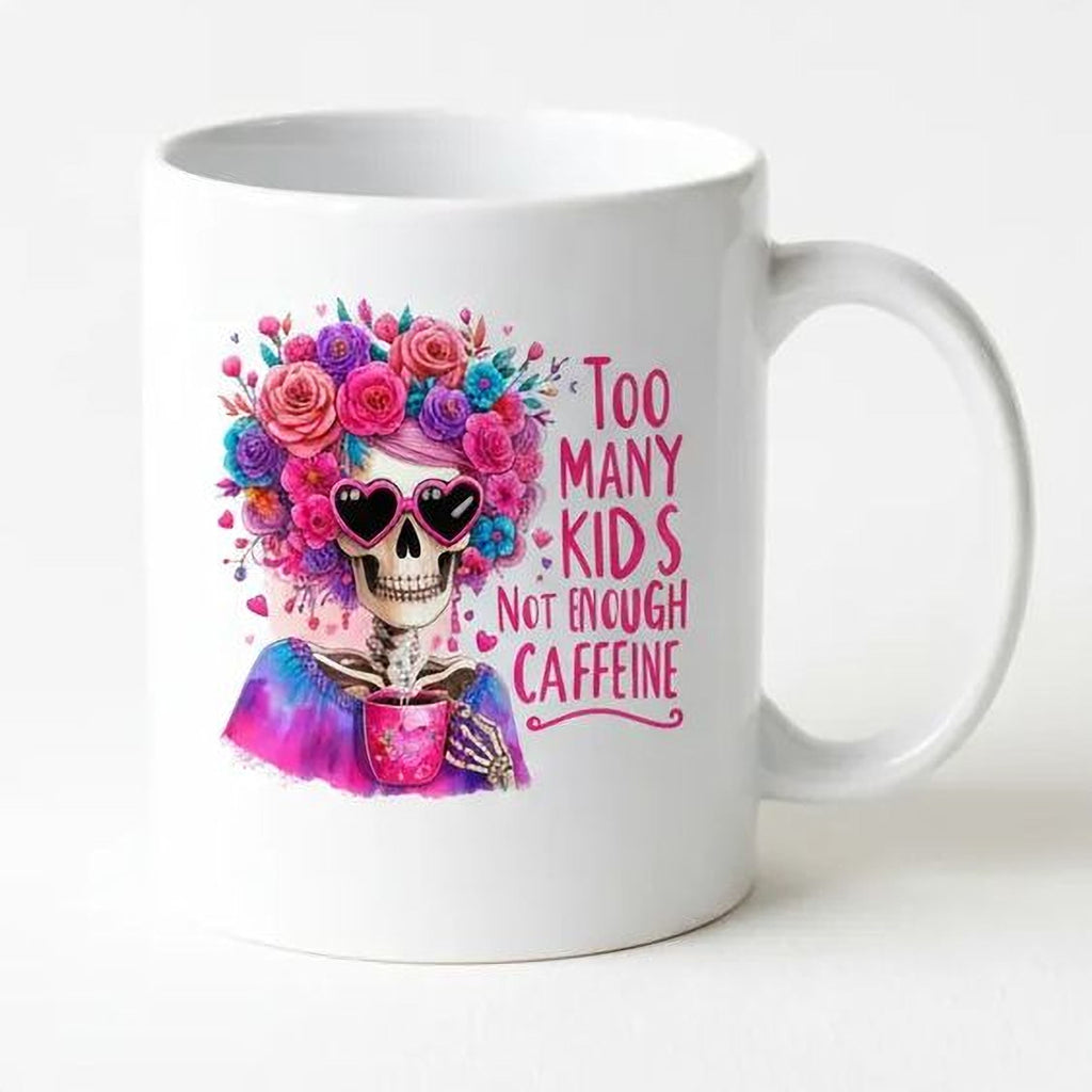 White ceramic mug side view with colorful floral crown skull and “Too Many Kids” coffee quote design.