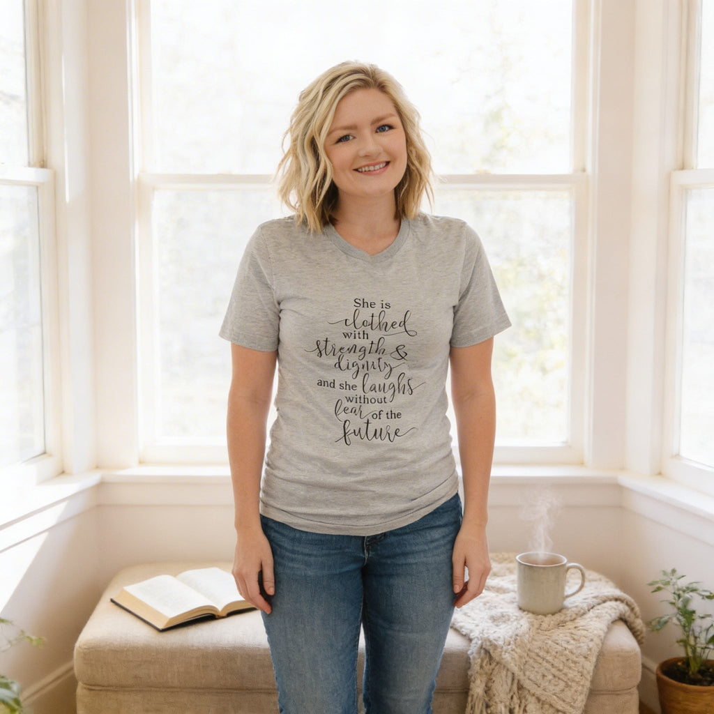 Light heather gray women's graphic T-shirt with "She is clothed..." verse on front.