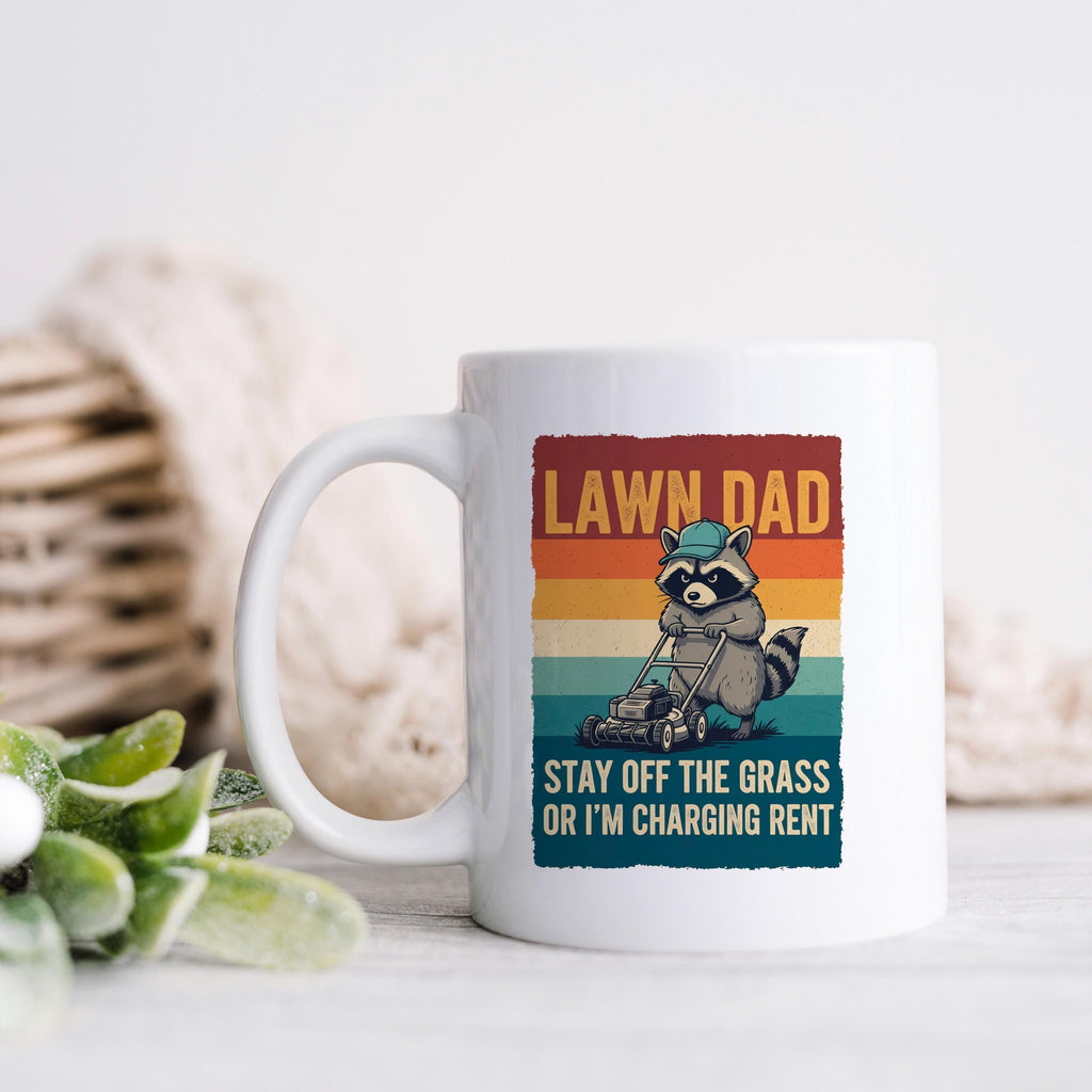 White coffee mug with raccoon mowing graphic and “LAWN DAD” phrase
