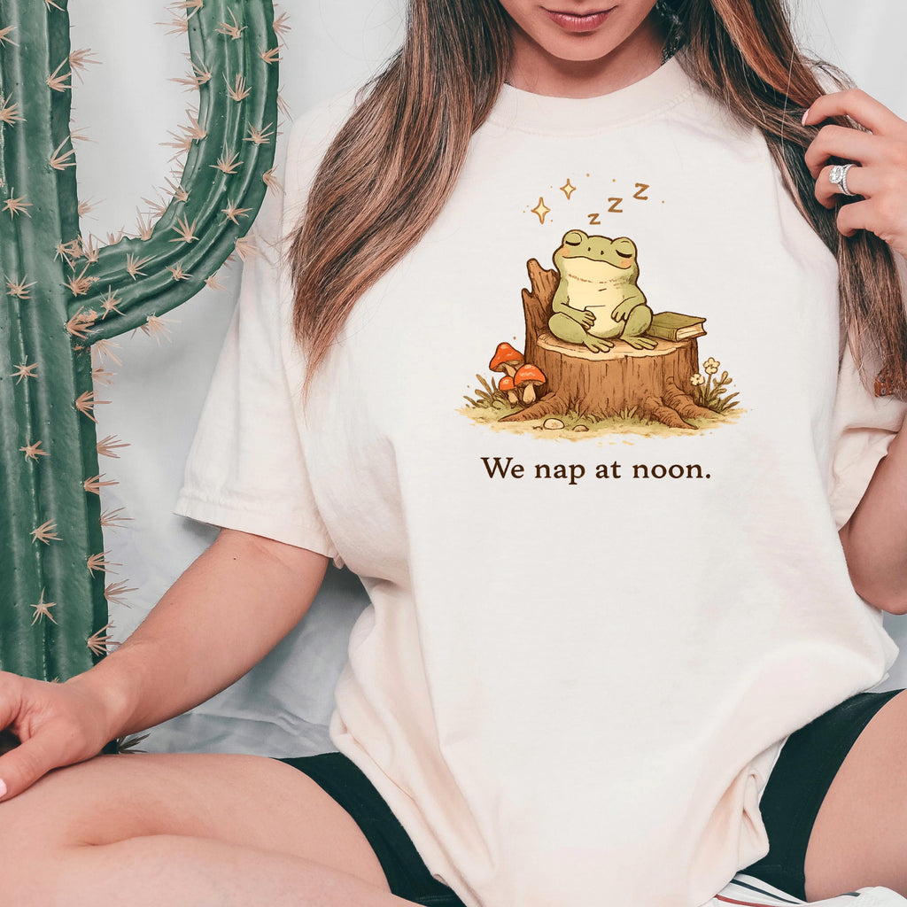Ivory T-shirt with sleeping frog graphic and “We nap at noon.” text.