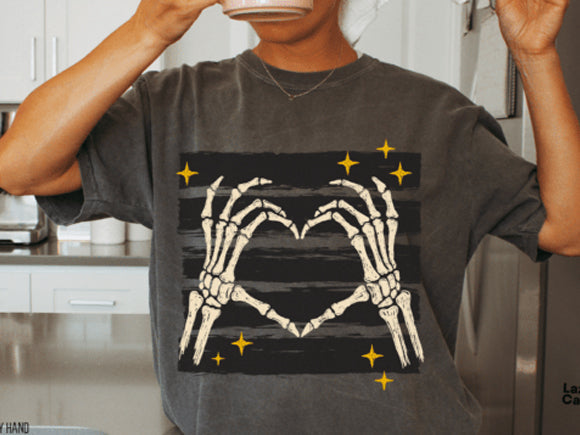 Dark graphic tee with white skeleton hands forming a heart and gold sparkle accents