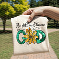 White graphic T-shirt with 'Be still and know' text and flower emblem
