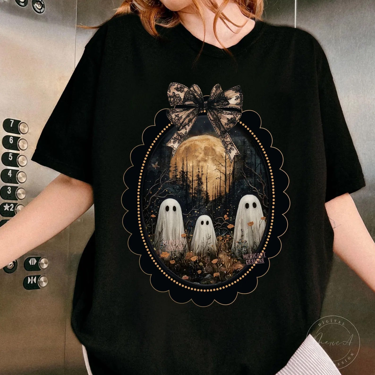 Black graphic tee with framed ghost figures, forest scene, and bow accent