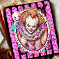 Black graphic tee with pink frame showing Pennywise clown face with orange hair
