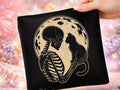 Black graphic tee with cat and skeleton design on the front