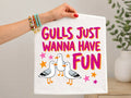 White graphic tee with pink/purple text, cartoon gulls, stars, and colorful accents