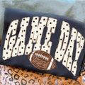 Dark tee with distressed white lettering blocks and a brown football graphic