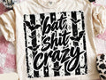 Bat-themed graphic tee with large black distressed text design on a light base
