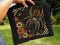 Black graphic tee with large spider design and orange floral accents