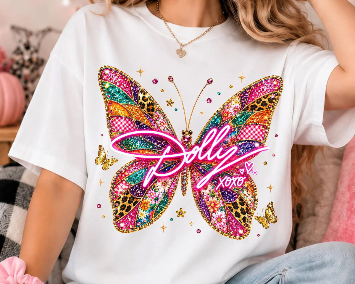 White butterfly graphic T-shirt with colorful jeweled wings and 'Dollie' script.