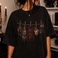 Black graphic tee with western-style hanging character illustration and small text block