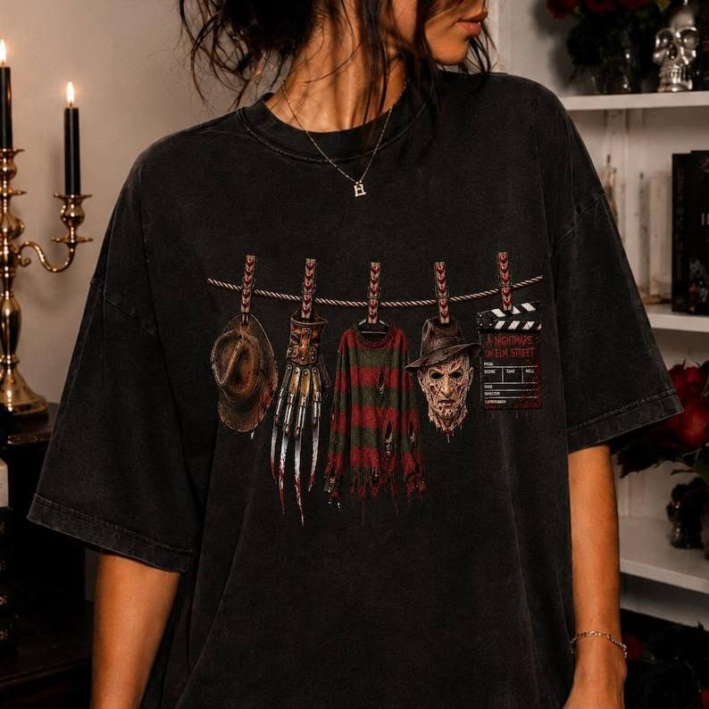 Black graphic tee with western-style hanging character illustration and small text block