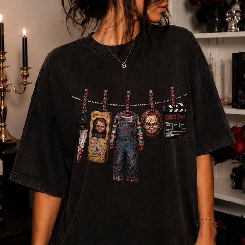 Black graphic tee with clothesline-style Chucky character artwork across chest