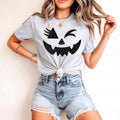 Grey graphic tee with black jack-o'-lantern face; front knot detail.