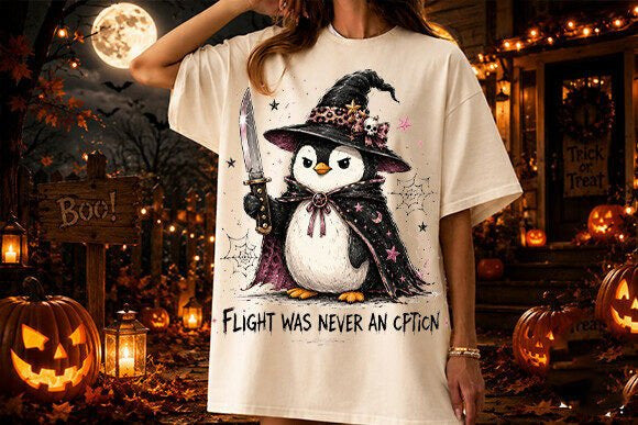 Cream graphic tee with witch penguin illustration and 'Flight Was Never an Option' text