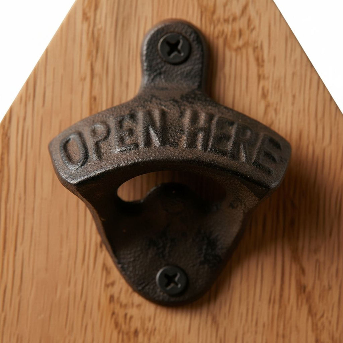 Close-up of black bottle opener on a wooden motorcycle sign with engraved lettering.