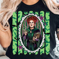 Black graphic tee with green forest-style backdrop and ornate portrait illustration