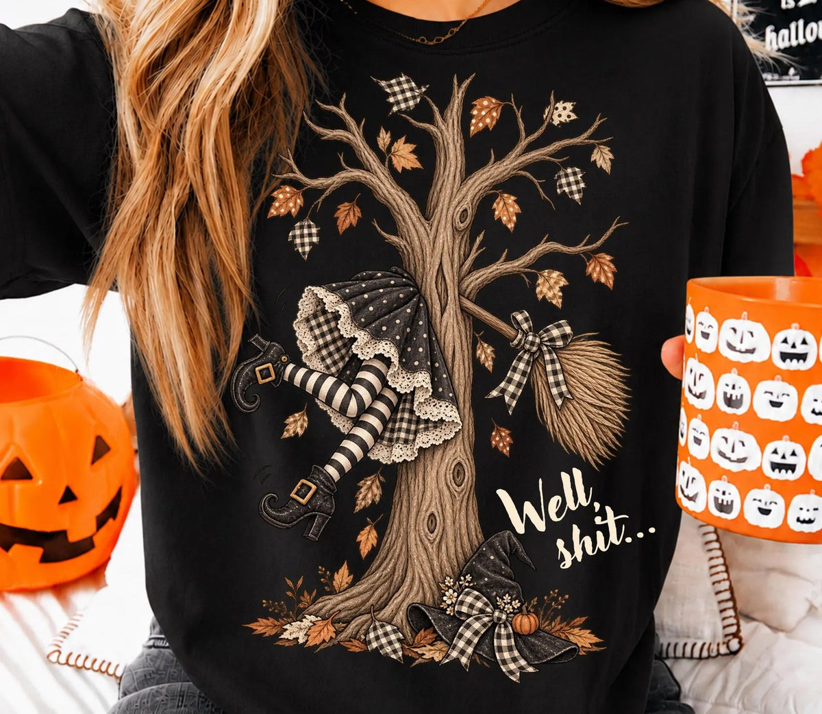 Black graphic tee with witch-themed tree, broom, and autumn leaves print