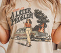 Cream graphic tee with 'A LATER PROBLEM' text and burning car illustration