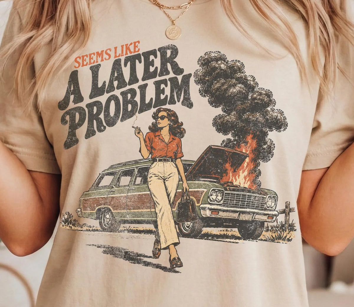 Cream graphic tee with 'A LATER PROBLEM' text and burning car illustration