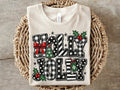 White graphic tee with festive holiday word print, stars, bow, and holly accents