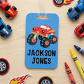 Blue monster truck backpack name tag with 'JACKSON JONES' text and hanging loop