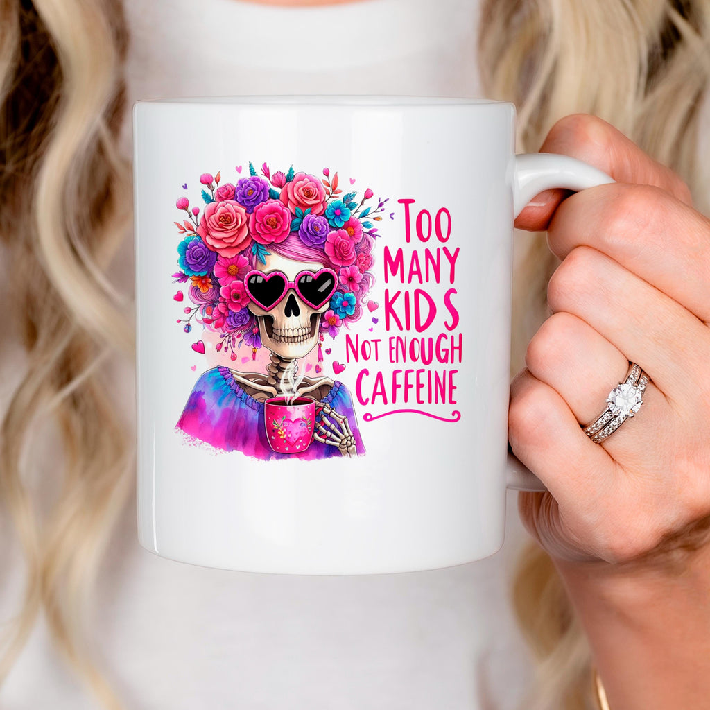 White ceramic mug with colorful floral crown skull and pink “Too Many Kids” text, right handle.