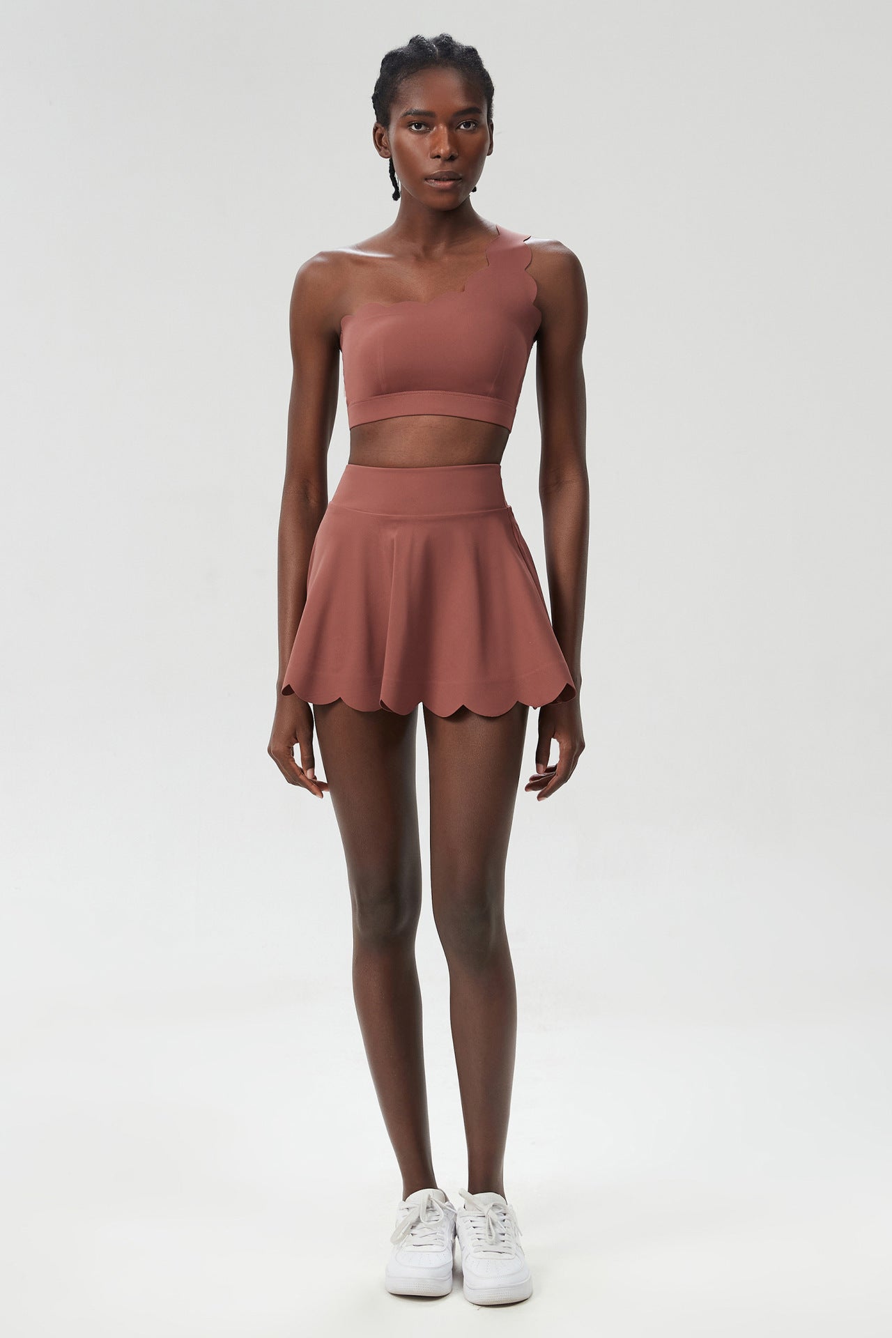 Terracotta sleeveless sports two-piece set with cropped top and scalloped skater skirt.