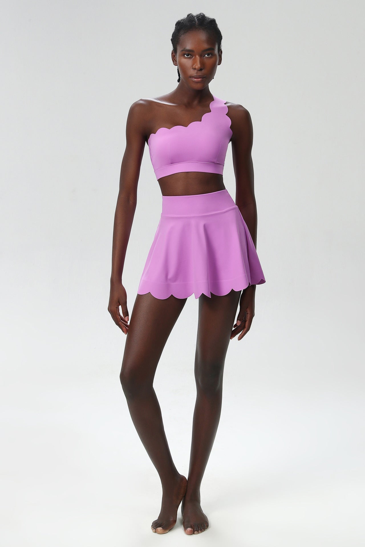 Purple one-shoulder sports two-piece set with cropped top and scalloped skater skirt.
