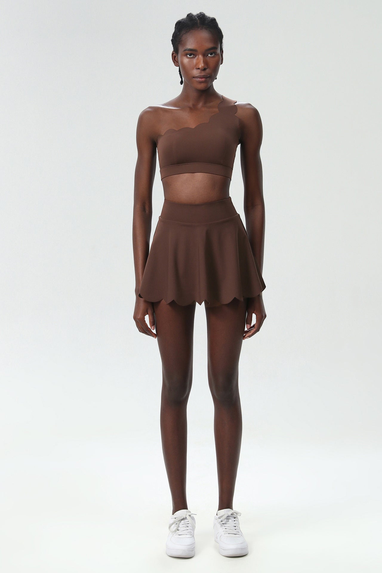 Brown one-shoulder sports two-piece set with cropped top and scalloped skater skirt.