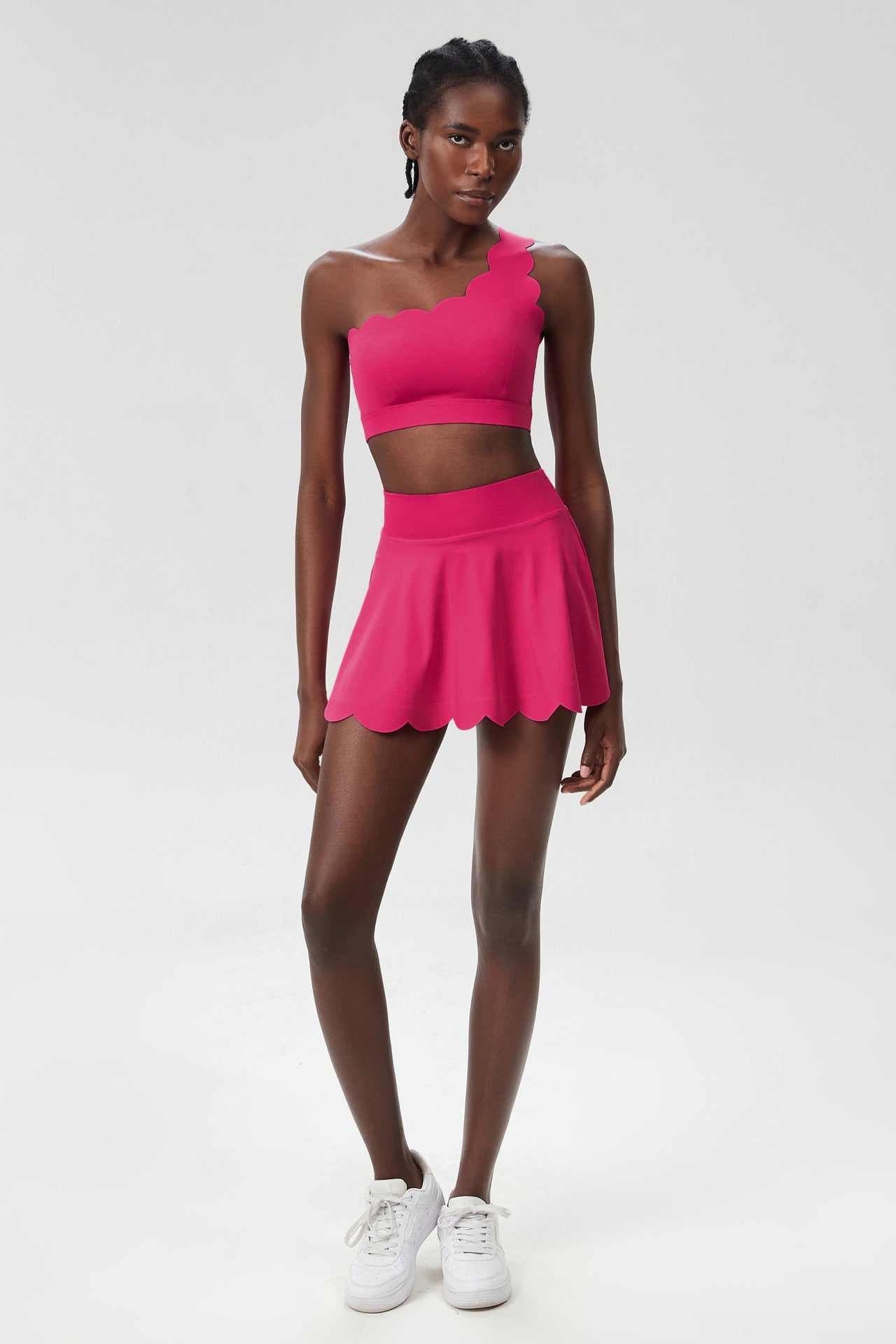 Magenta one-shoulder sports two-piece set with cropped top and scalloped skater skirt.