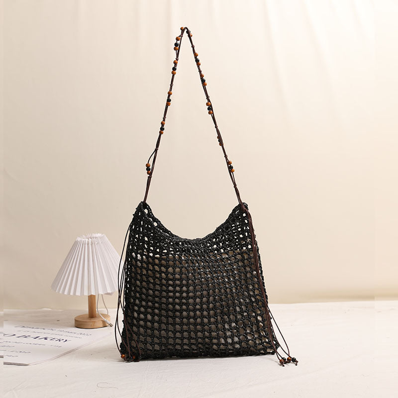 Black woven straw hobo bag with openwork lace-up lattice and beaded strap ties