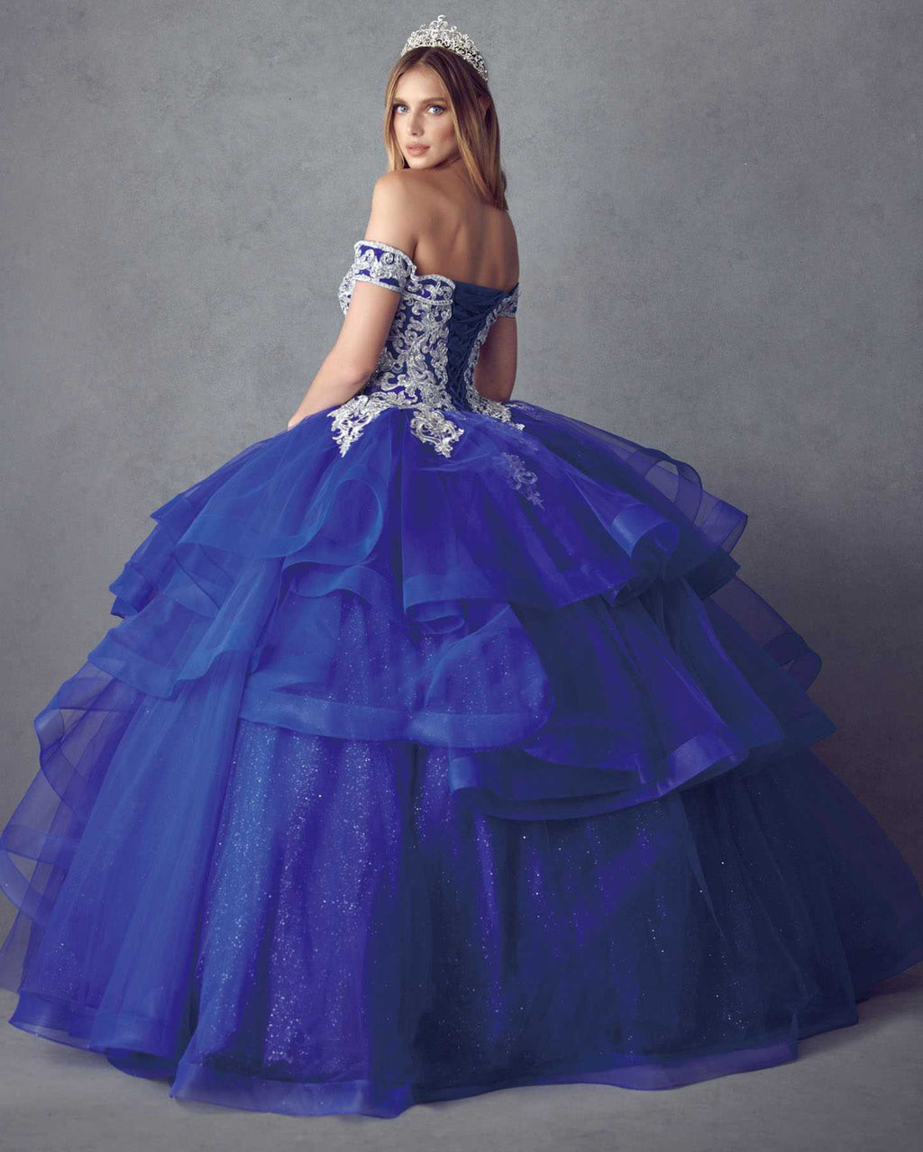 Navy blue ball gown with off-shoulder neckline, glitter details, and layered tulle skirt