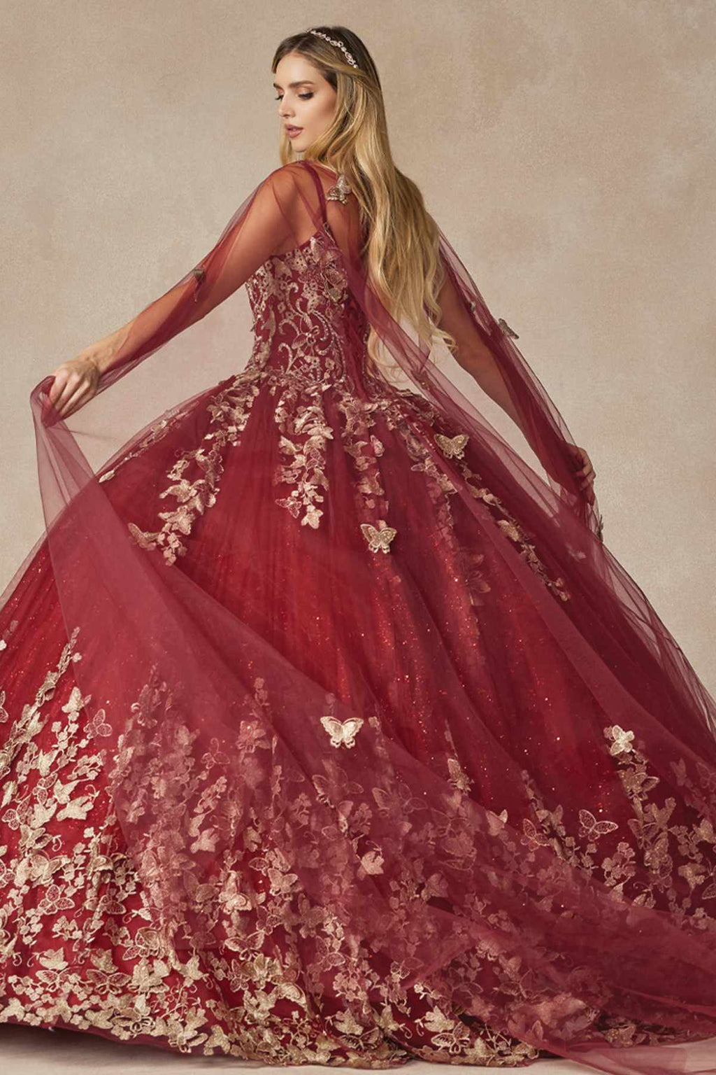 Burgundy ball gown with butterfly appliques, full skirt, and flowing sheer cape