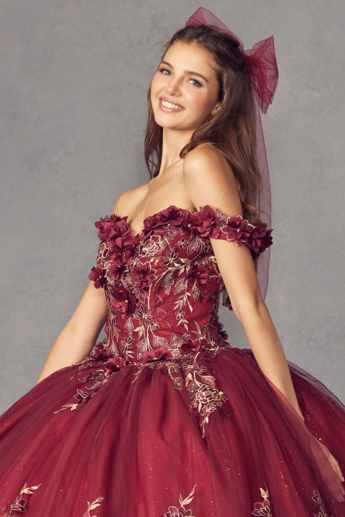 Burgundy off-shoulder ball gown with floral appliques, ruffled neckline, bow detail