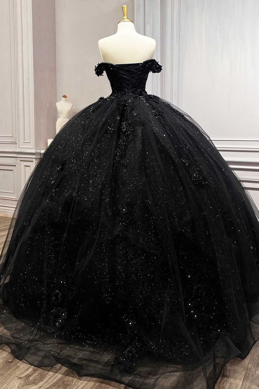 Black off-shoulder ball gown on mannequin with glitter tulle skirt and layered volume