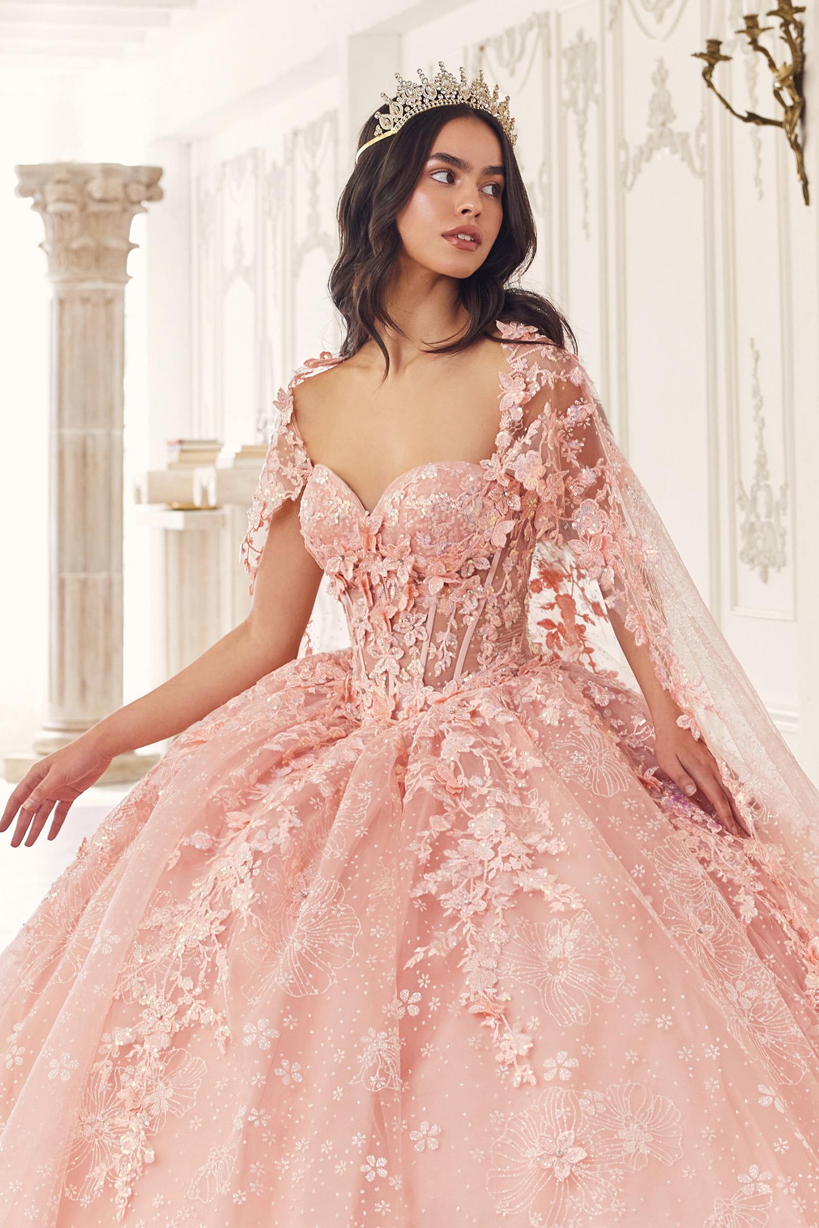 Blush pink quinceañera gown with sweetheart neckline, lace sleeves, and sheer tulle cape