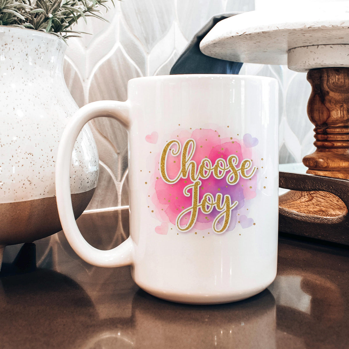 White ceramic coffee mug with pink watercolor "Choose Joy" on front and side handle