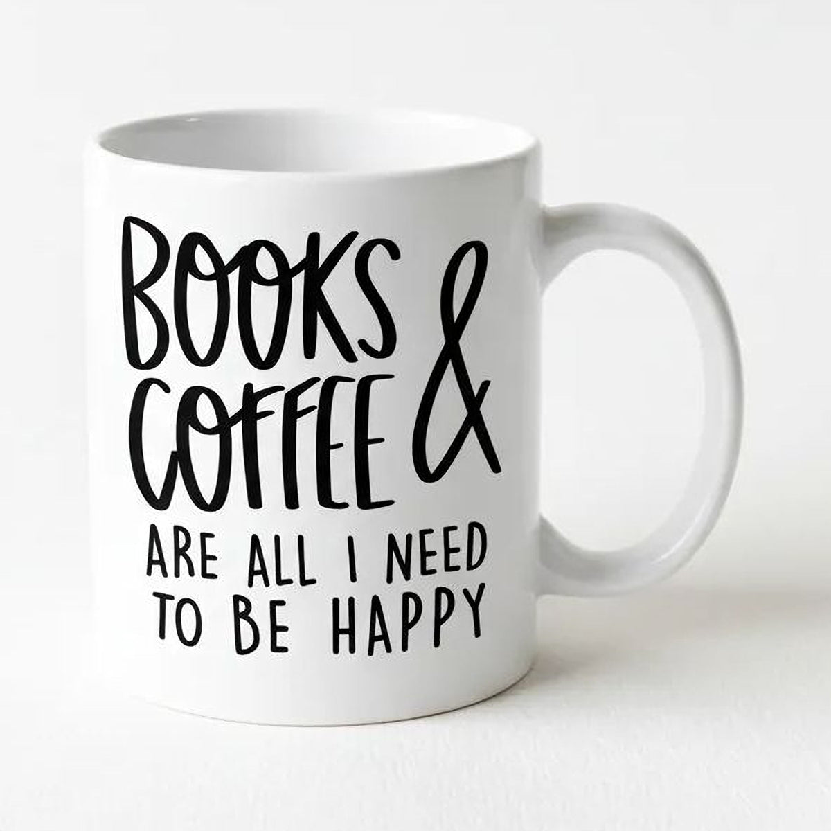 White ceramic coffee mug with 'BOOKS & COFFEE' quote and 'TO BE HAPPY'