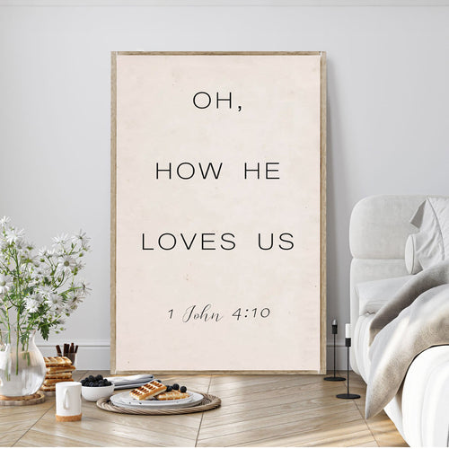 Canvas wall sign reading “OH, HOW HE LOVES US” and “1 John 4:10”