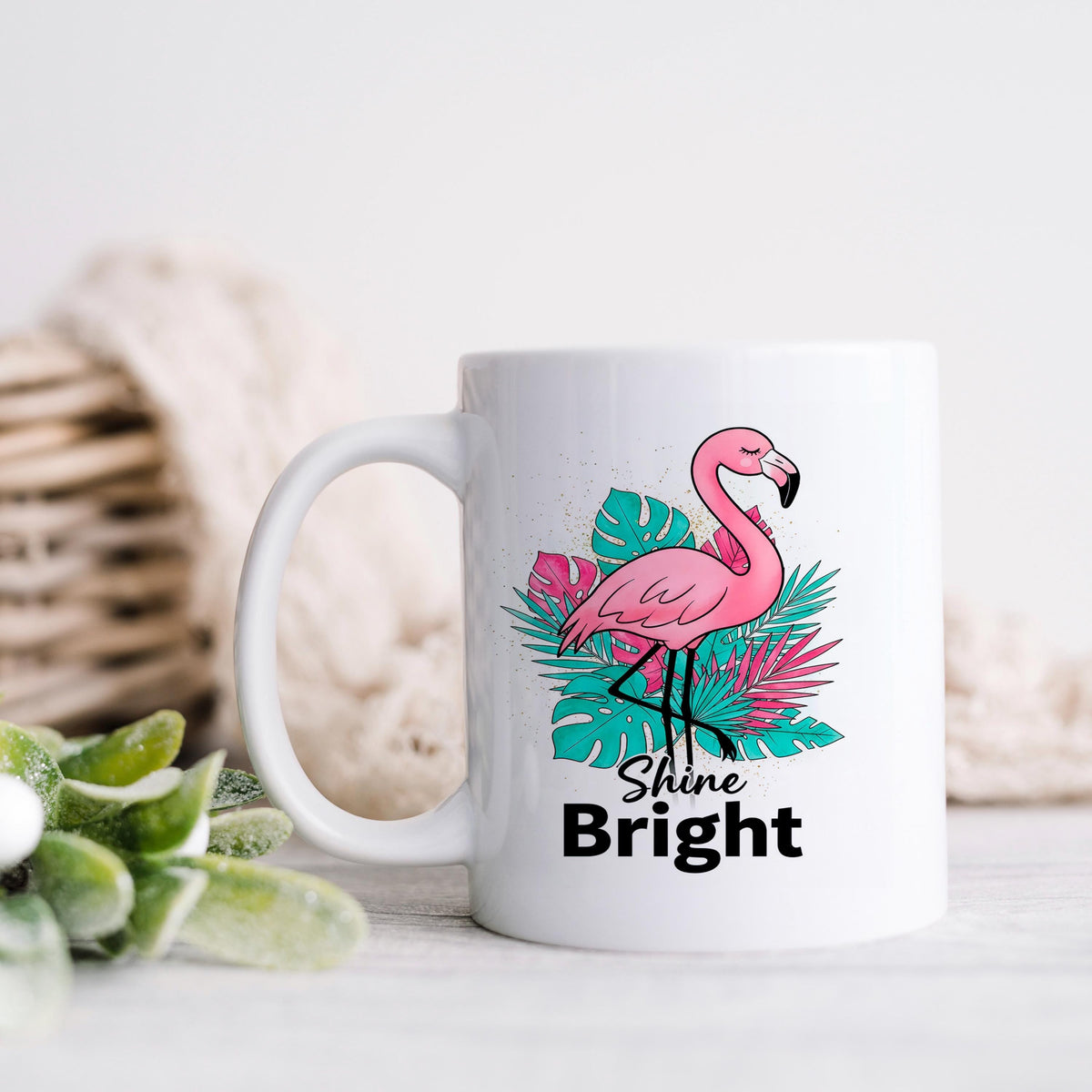 White ceramic coffee mug with pink flamingo and tropical leaves, text “Shine Bright”