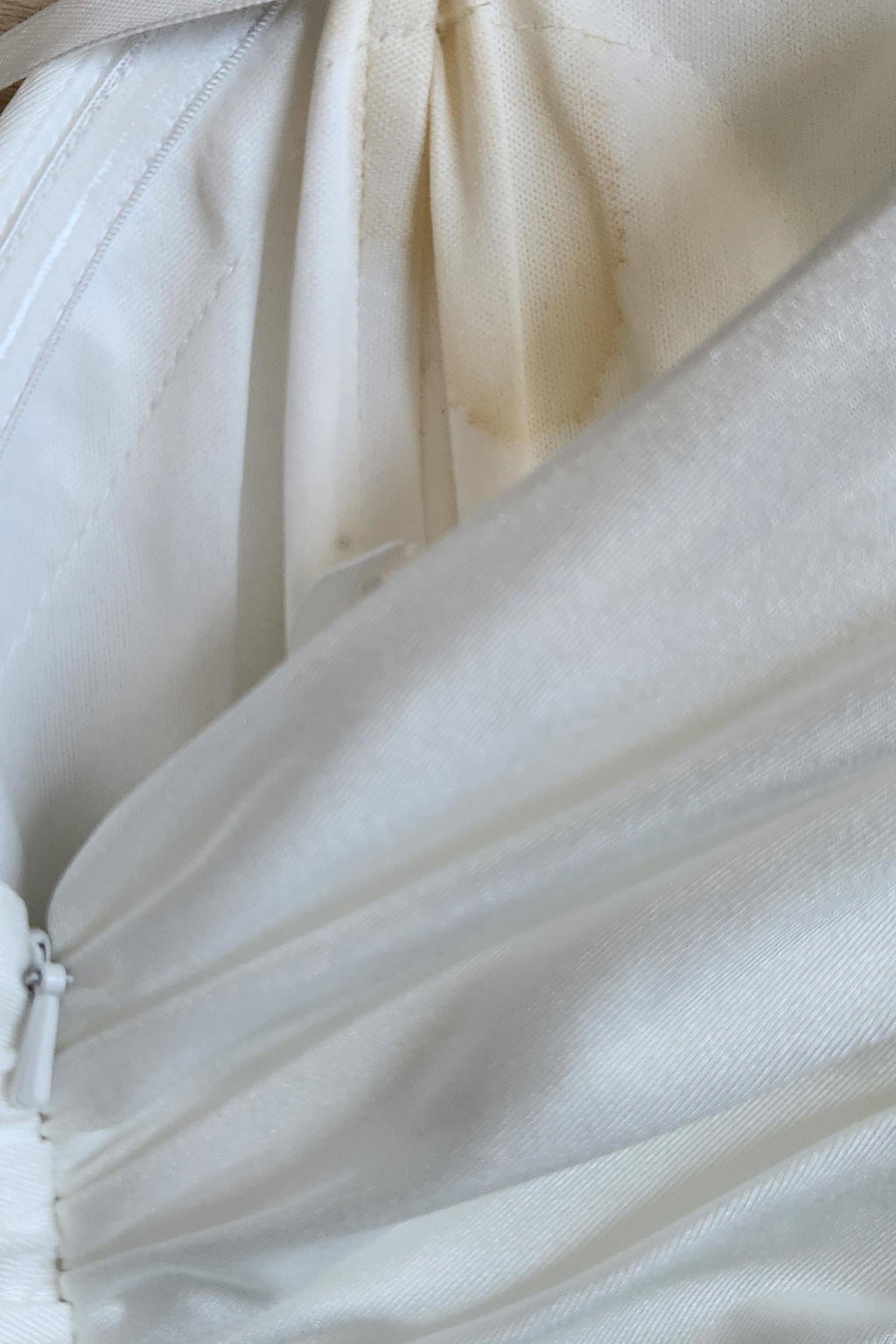 Off-white bridal gown fabric close-up with seams and gathered layers