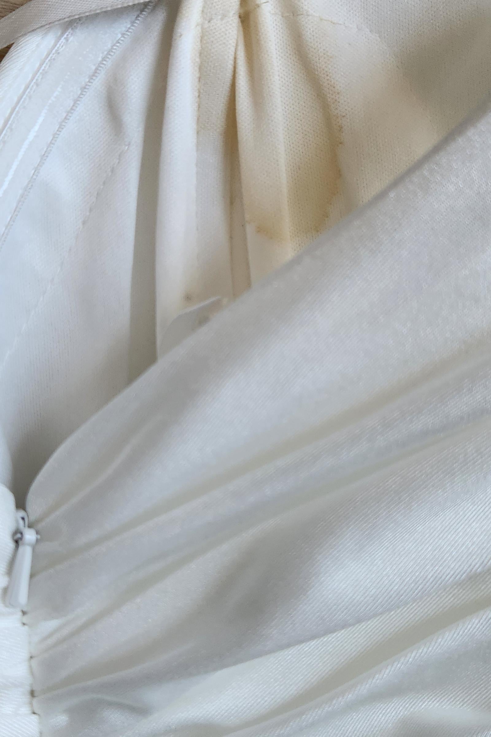 Off-white bridal gown fabric close-up with seams and gathered layers