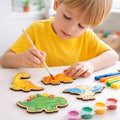 Kids painting wooden dinosaur cutouts with brush and paints, children’s craft kit