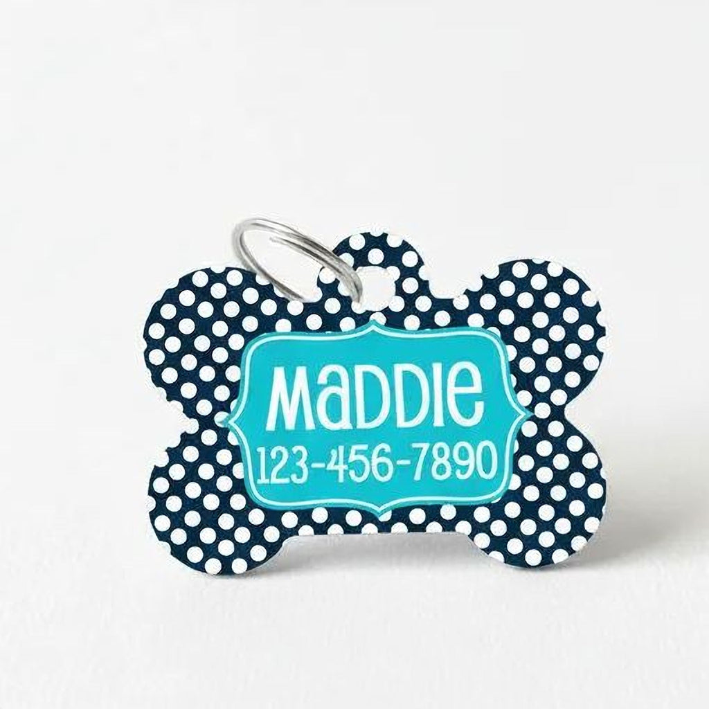 Navy dog ID tag with large white dots, teal nameplate, and metal attachment ring