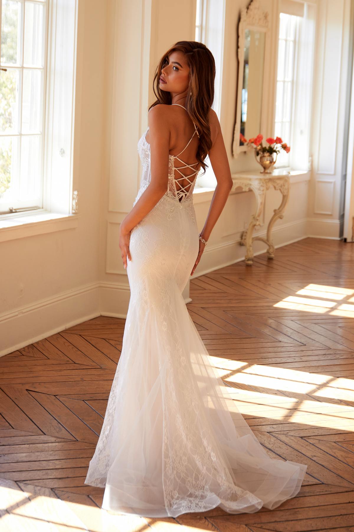 Off-white lace mermaid bridal dress with spaghetti straps and open lace back detail.