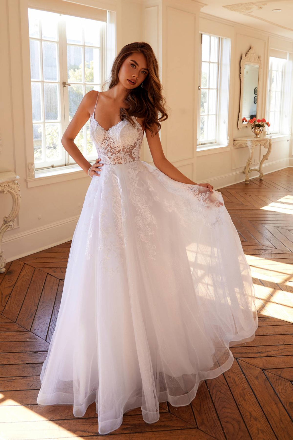 White lace wedding gown with spaghetti straps, fitted waist, and voluminous tulle skirt