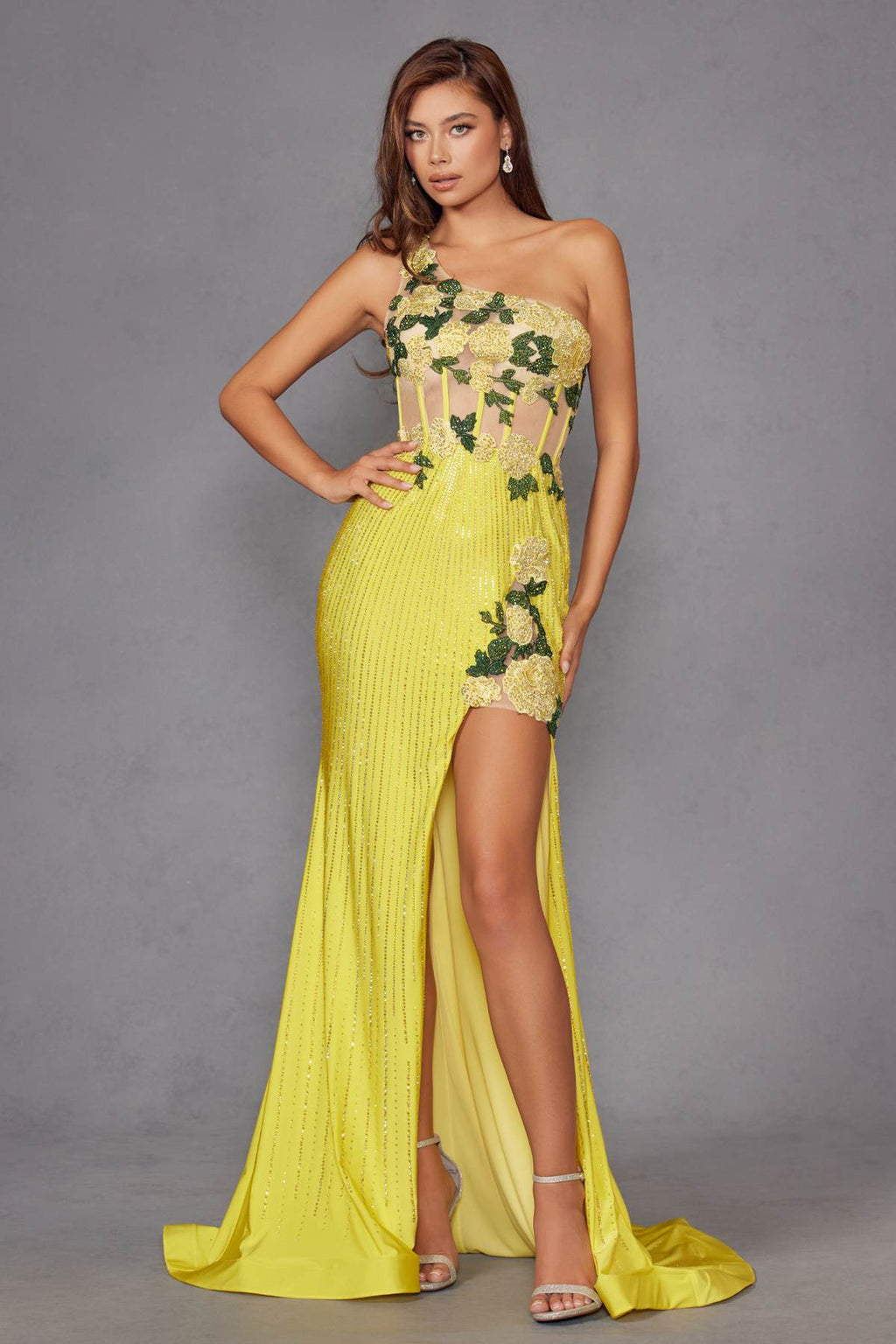Front view of one-shoulder fitted evening gown in bright yellow with floral applique and slit