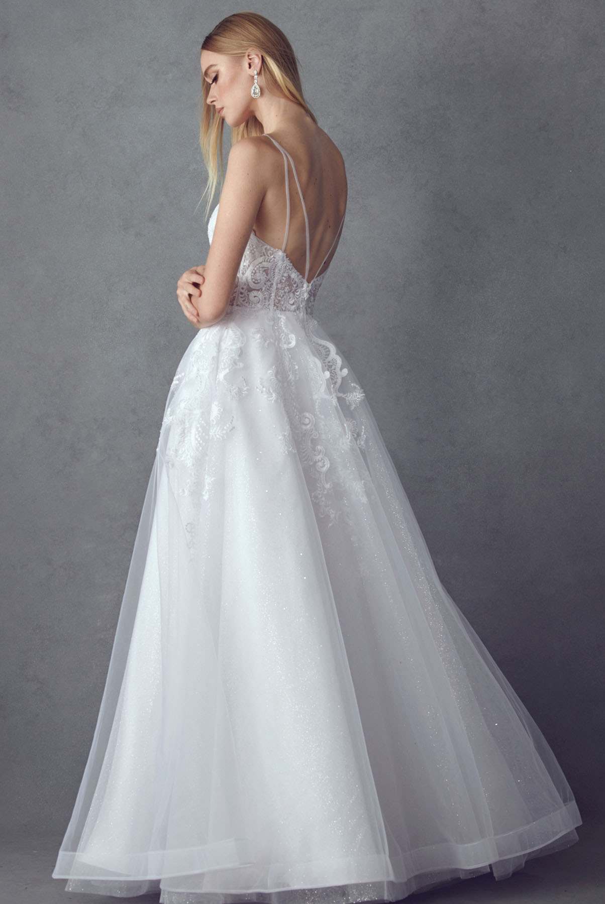 White A-line tulle wedding ball gown from side/back view with lace bodice and straps
